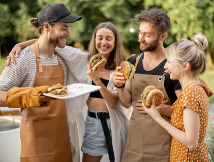 A group of friends laughing and working together in a kitchen.